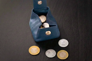 Blue leather coin pouch with coins on a dark surface

